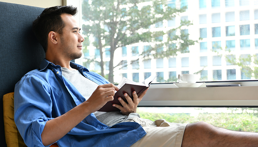 Man staring out his window cheerfully